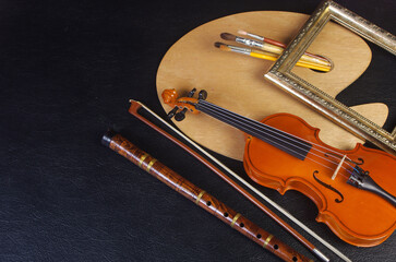 Art attributes. Music and painting. Violin, pipe, clarinet, art palette and brushes on a black...