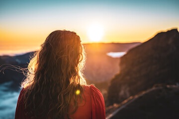 Fototapeta premium Beautiful woman in red dress enjoying sunny evening atmosphere on Pico do Ariero. Verade do Pico Ruivo, Madeira Island, Portugal, Europe.