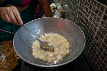 Hot fried snacks being taken out from the kadhai or pan full of oil, ghee, butter. Shanka pali, shakkar para, sweets, namkeen, deep fry, Diwali, Deepawali, faral, prasad, dish, healthy, cholesterol.