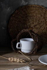 White coffee cup in a wicker basket on a wooden table