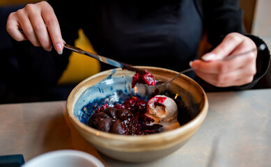 Young woman hand eating chocolate fondant dessert using knife and fork fom bowl