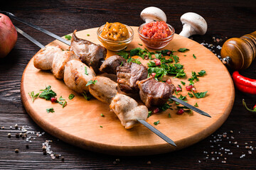 Assorted barbecue: pork neck barbecue, chicken fillet barbecue, onion with tkemali and satsibeli on a wooden board.