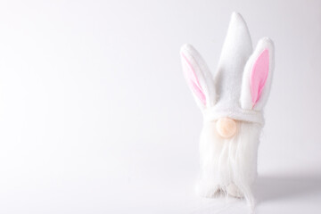 A Scandinavian toy gnome in white clothes and pink ears. Copy space on a white background