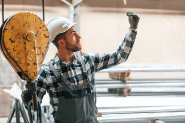 Communicate with crane operator. Factory male worker in uniform is indoors