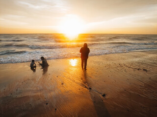 silhouette of poeple enjoying the beach during golden sunset.