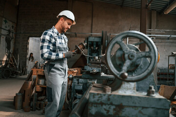 Fototapeta na wymiar Metal processing. Factory male worker in uniform is indoors