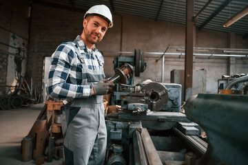 Metal processing. Factory male worker in uniform is indoors