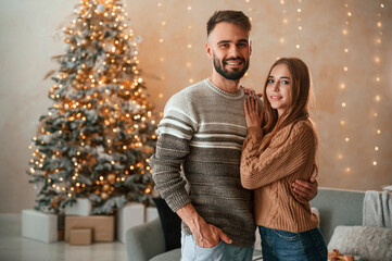 Standing and smiling. Lovely young couple are celebrating New Year at home