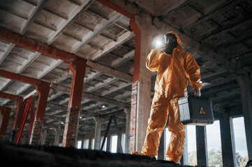 Bottom view. Man dressed in chemical protection suit in the ruins of the post apocalyptic building