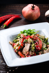 Traditional Georgian salad with chicken fillet combined with fresh tomatoes, cucumbers, herbs, pomegranate seeds.