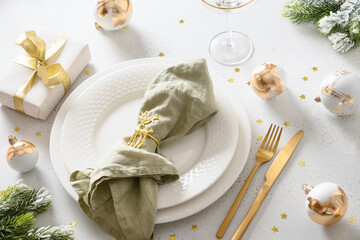 Beautiful Christmas festive table setting with white plate, champagne glass, golden balls and napkin ring as deer on white background. Close up. Xmas dinner.