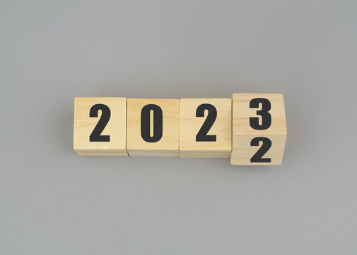 Wooden Cubes With Numbers 2023 And 2022 On Gray Background. Flipping Of 2022 To 2023. Changes In New Year.
