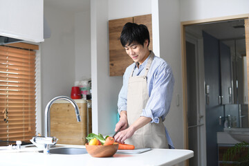 キッチンで料理をするエプロン姿の若い男性