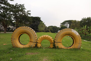 A Decoration from 3 Tires Painted in Yellow in a Park