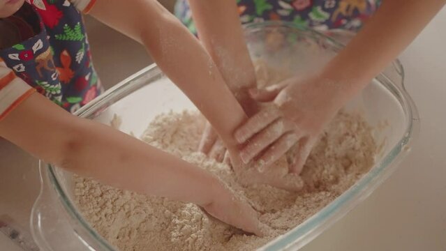 Top view, children's hands, close-up. Children mixing flour, in a bowl. Caucasian children, helping their mother to prepare the dough for the pie. Cooking homemade bread. Girls are learning to cook
