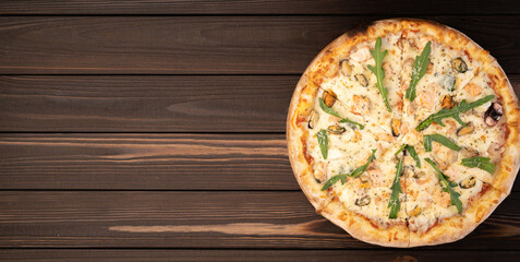 Gourmet seafood pizza on the wooden table with the ingredients of fresh scampi, mussels and clams. Banner