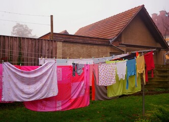 bunte wäsche auf einer wäscheleine zum trocknen aufgehängt, als hintergund eine wirtschaftsgebäude, wäsche an der frischen luft getrocknet