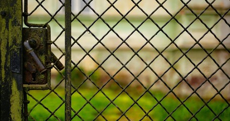 ein gittertor aus draht, geschlossenes tor, türklinke heruntergedrückt, alt, verwittert,. querformat