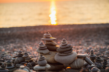 Stones pyramid on pebble symbolizing zen, harmony, balance. Ocean water at sunset in the background