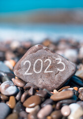 The inscription 2023 on a stone on the seashore.New Year 2023