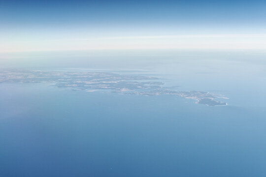 Aerial view from airplane window to Gotland island in Baltic sea, beautiful largest island in Sweden. Beautiful hazed sky aerial view to blue baltic sea, aerial seascape background