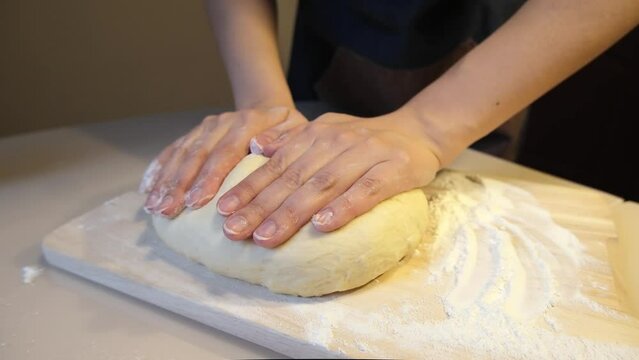 Women's hands knead butter dough for buns on a table covered with flour. High quality FullHD footage with slow motion 