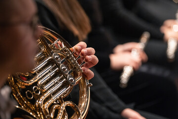 A close up of a French horn player playing the instrument during a classical symphony orchestra concert