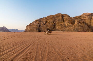 Fototapeta na wymiar A view of travellers at sunrise in the desert landscape in Wadi Rum, Jordan in summertime
