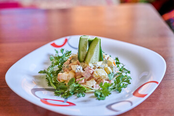 a salad on a white plate with red trim around the edge and an avocal cut in half to make it look like