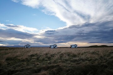 Village with white houses in front of a field with a cloudy sky in the background