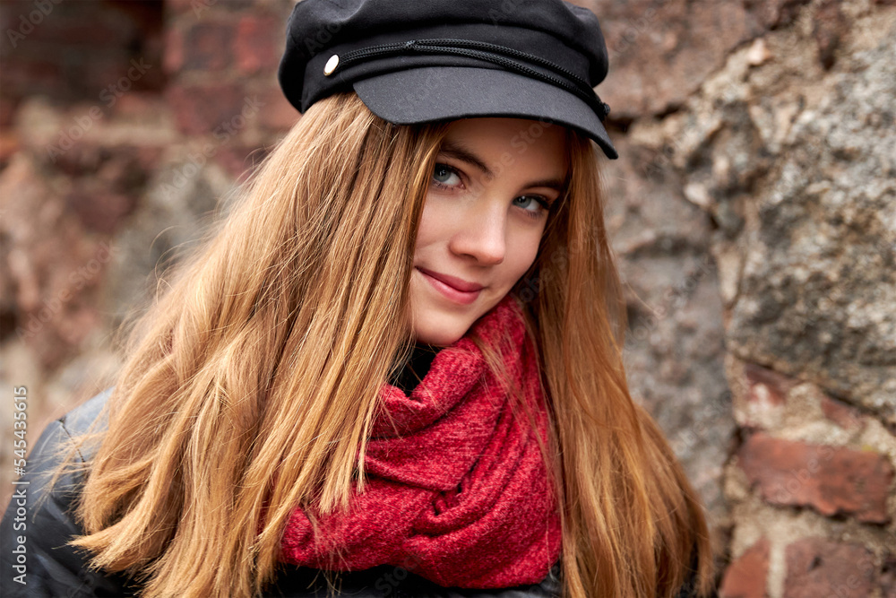 Canvas Prints Girl in a black cap with a red scarf against a brick wall