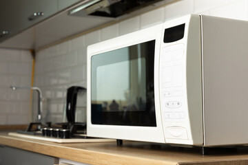 Modern white microwave on the kitchen countertop.Using microwave everyday in the kitchen. The concept of cooking. - obrazy, fototapety, plakaty