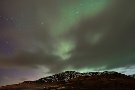 Northern Lights On A Starry Night Over Snow Covered Rocky Mountains, Iceland