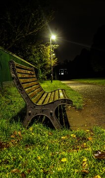 Bench in park surrounded by grass in night