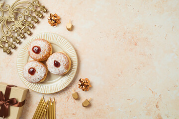 Jewish holiday Hanukkah concept with traditional donuts, menorah and gift box on stone background....