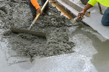 Construction worker pouring cement to create new sidewalk on side of house