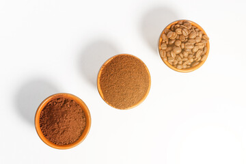 Three cups of coffee beans, ground coffee and cocoa for comparison.