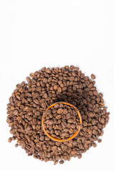 A small saucer with coffee beans stands on a pile of coffee on a white background.