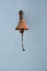 Old hanging old bell from blue wall