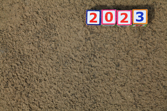 Inscription 2023. Toy square cubes and numbers on the sand on the river bank, that means coming New Year Eve. Christmas, holidays, celebration concept. New Year of 2023, year of black water rabbit