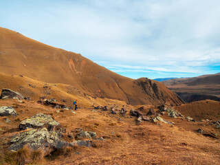 Autumn trekking on footpath alone Caucasus rocks. Solo trekking in the mountains. Travel photographer lifestyle, hiking hard track, adventure concept in autumn vacation.