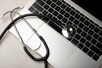 Laptop computer with stethoscope keyboard on black background. Modern medical information technologies. Software concept. Diagnostics and repair of computers and gadgets. flat view