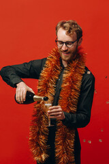 Red-haired handsome man in glasses and a golden boa raises a glass of champagne. Celebration of the new year.