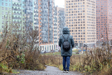 Woman looks at the houses under construction, urban landscape in late autumn. Building industry and real estate concept