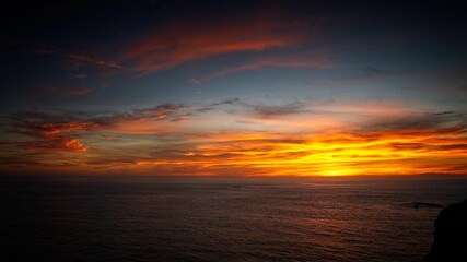 Fototapeta na wymiar Bright glowing sunset sky over a calm sea in Algarve, Portugal