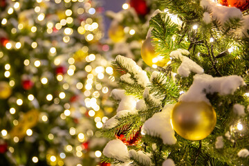 outdoor christmas decorations in city square. close up image of illuminated christmass trees with garlands, fairy lights and balls on defocused background