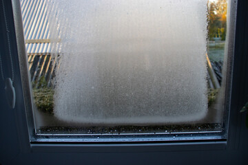 Frost on the window glass in the house. Condensed couple texture. Winter concept, a problem with...
