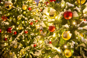 Fototapeta na wymiar christmas decorations in city square. close up image of illuminated christmass trees with garlands, fairy lights and balls on defocused background