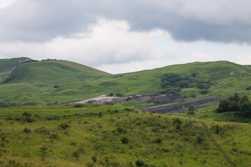 Obraz premium Beautiful dramatic landscape - panoramic view of green hills with trees and misty haze against a cloudy sky in Kislovodsk Stavropol territory and a space for copying