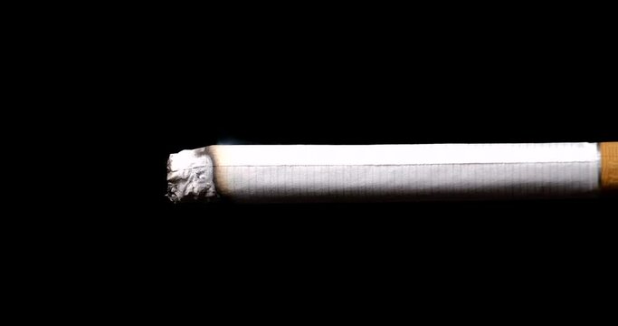 Time lapse close-up of a cigarette burning on a black background